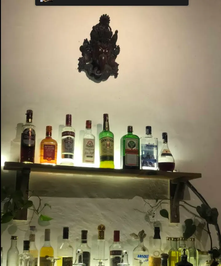 The bar's spirit and herbal-product shelf beneath a carved Himalayan deity.
