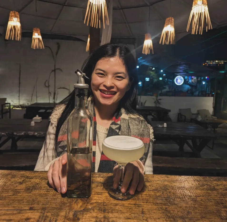 A guest smiling with a smoking signature cocktail in the garden.