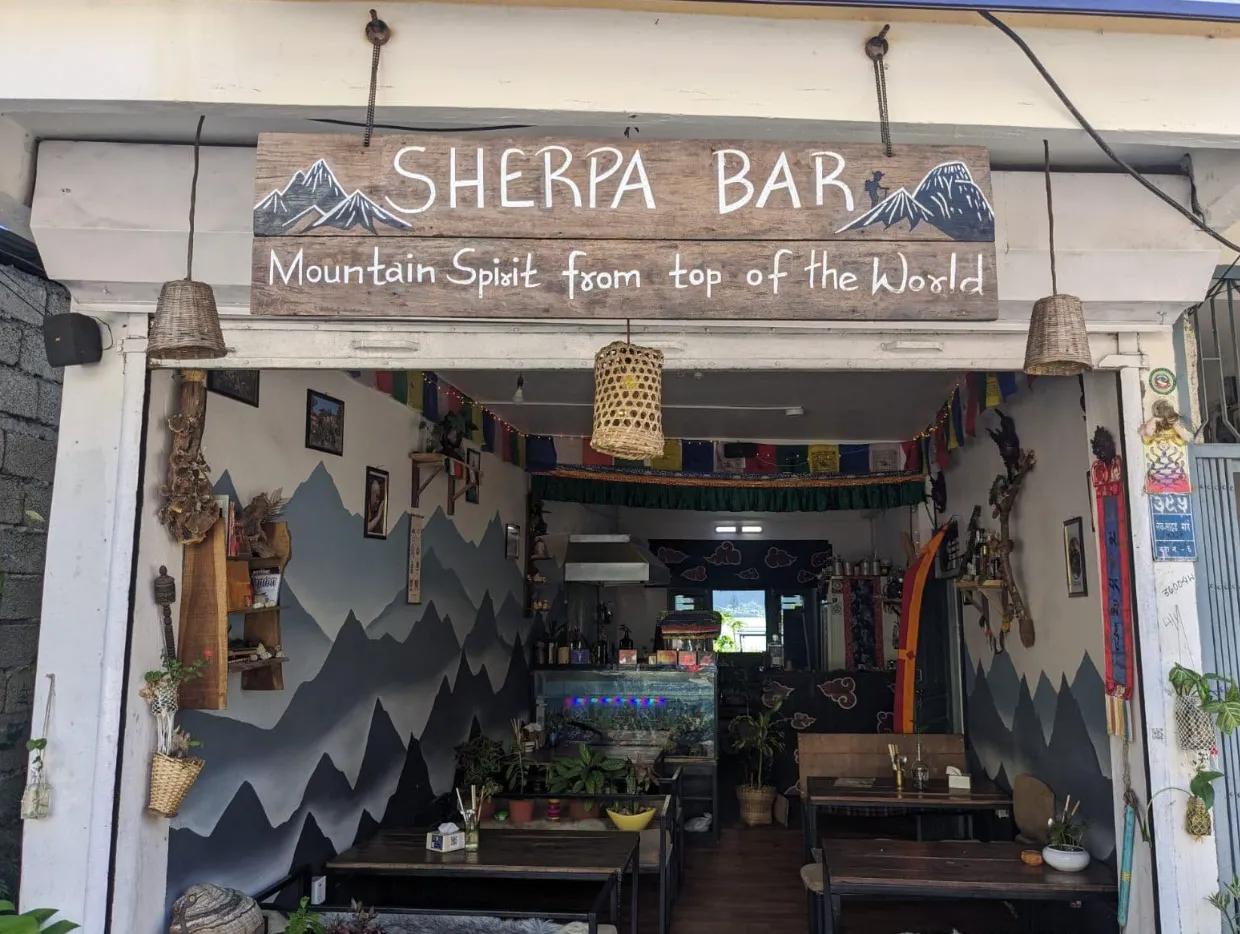 The hand-painted Sherpa Bar storefront on Lakeside Street in Pokhara, with a slate mountain mural framing the entrance.