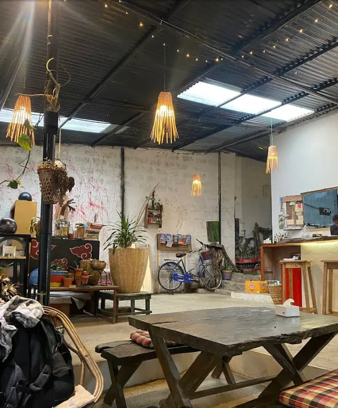 The wide communal interior with hanging lamps, bicycles and long tables.
